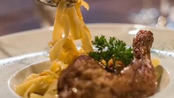 A plate with pasta and a piece of meat, possibly chicken, garnished with parsley.