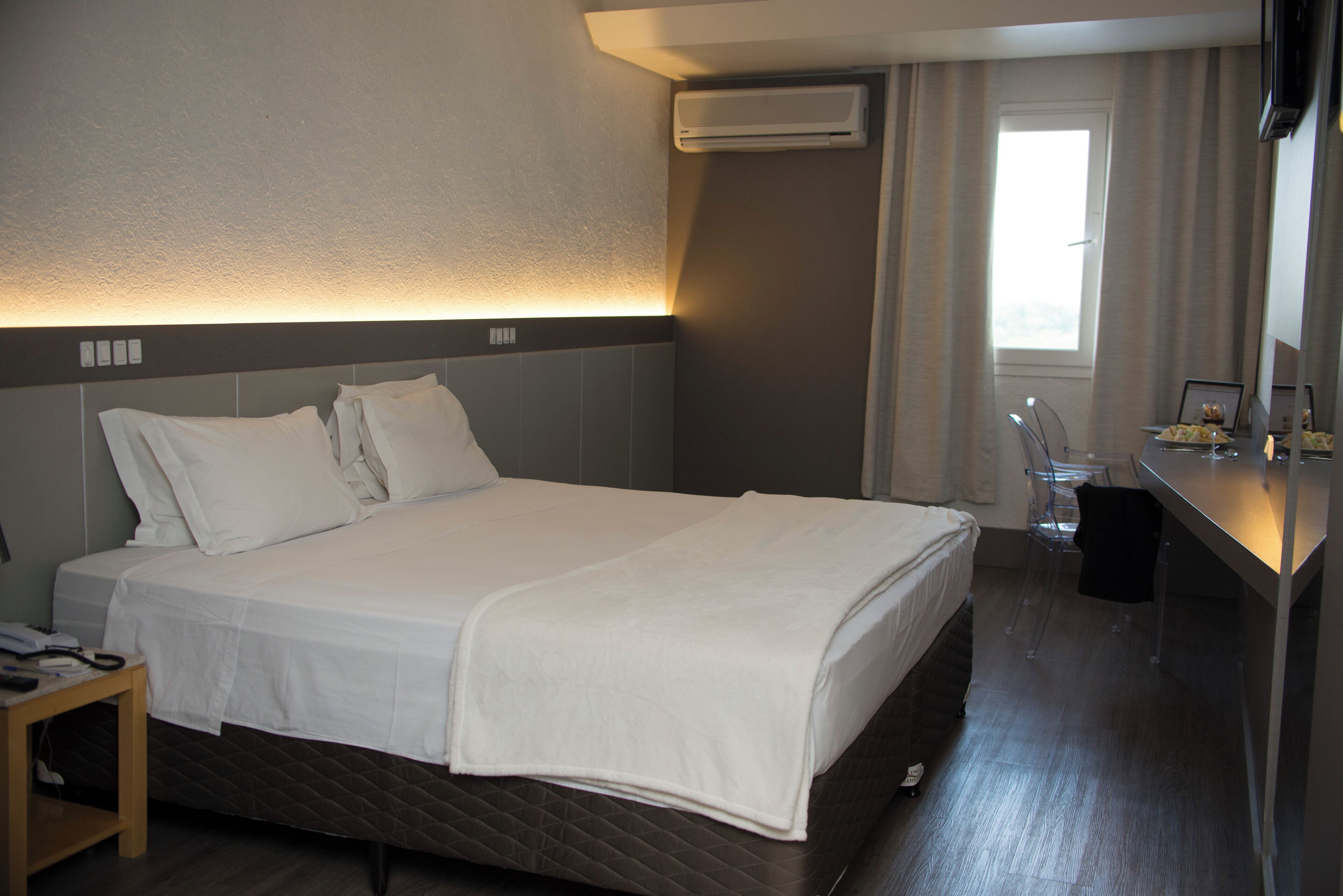 Ein Hotelzimmer mit Bett, Nachttisch und Schreibtisch mit Stuhl.