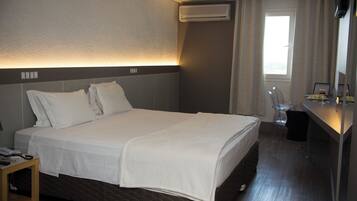 Ein Hotelzimmer mit Bett, Nachttisch und Schreibtisch mit Stuhl.