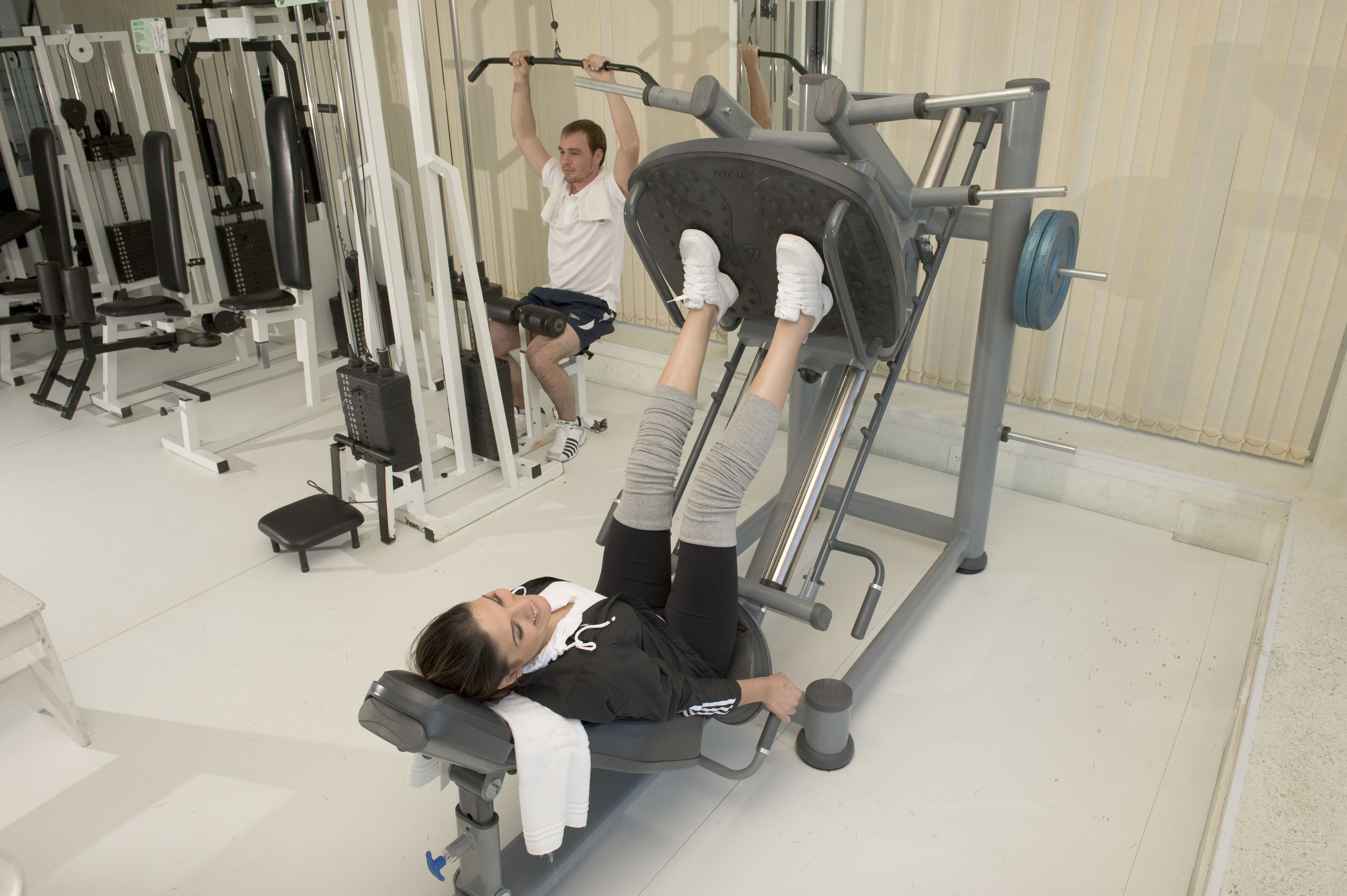 A gym with various exercise machines, including a leg press and a pull-up bar.