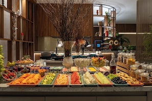 Buffet amb diverses opcions de menjar, incloent fruita, formatges i amanides.
