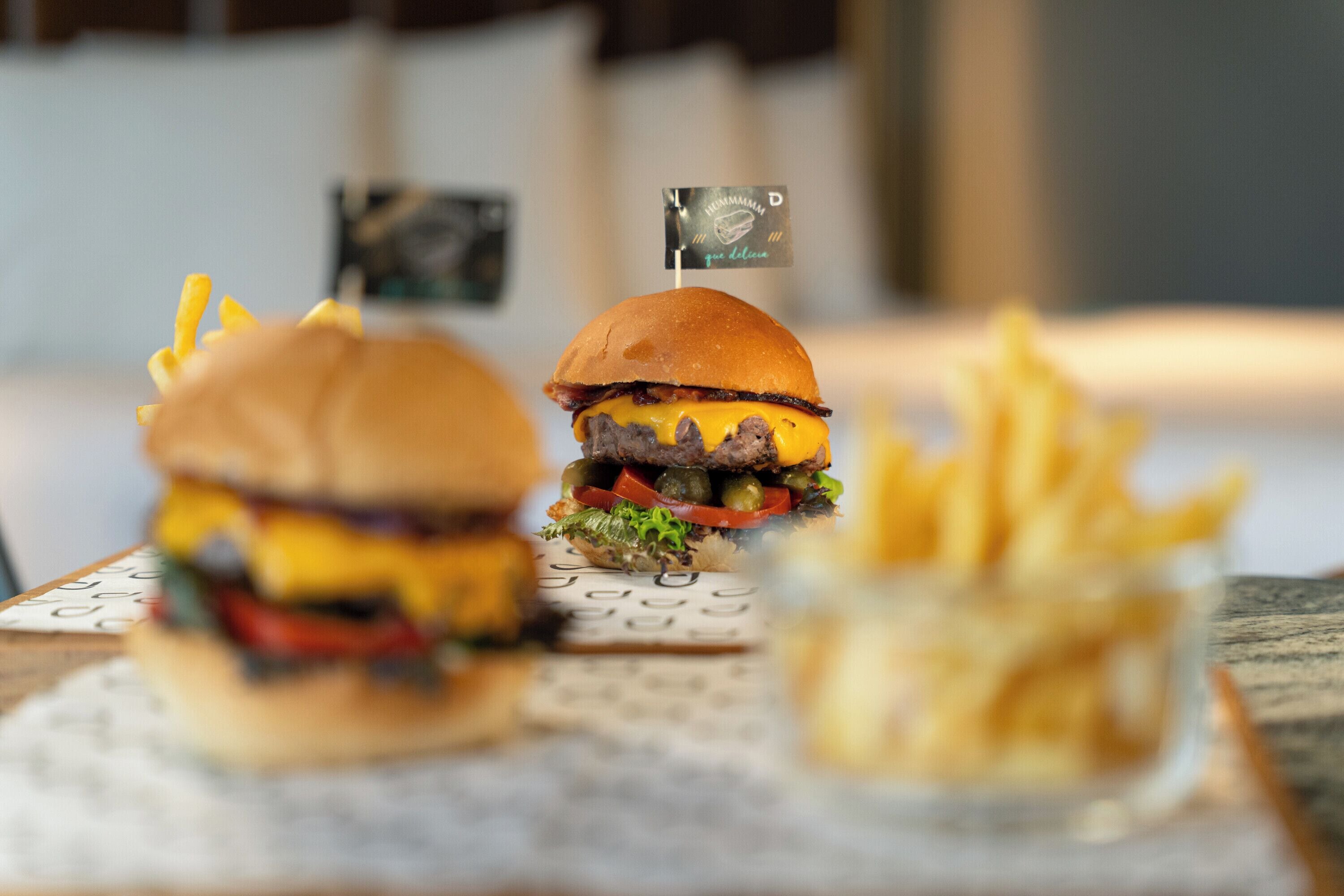 Dos hamburguesas y un tazón pequeño de papas fritas sobre una mesa con un mantel individual.