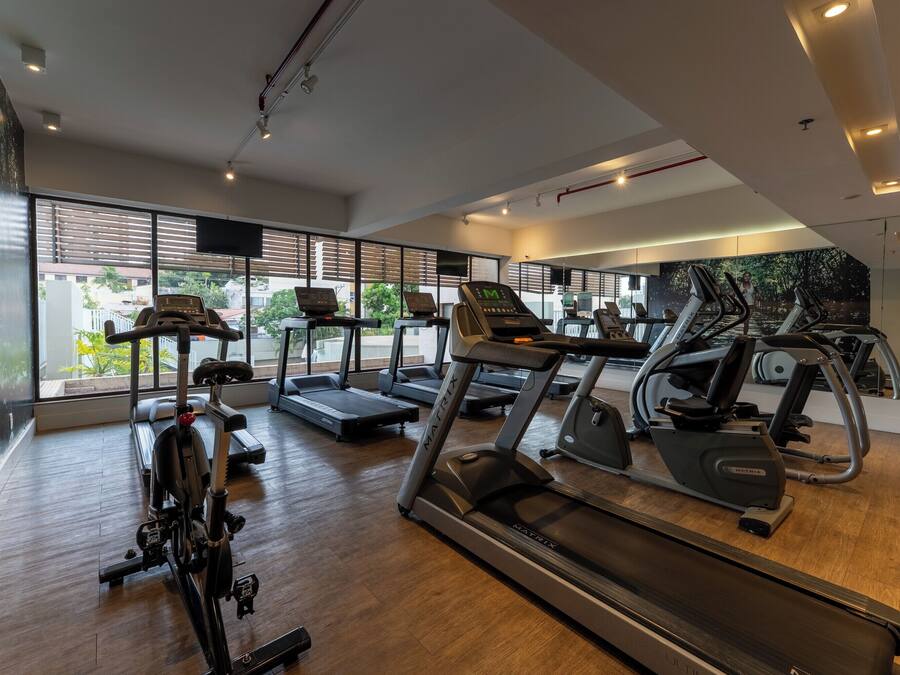 A modern gym with treadmills, elliptical machines, and weight equipment.