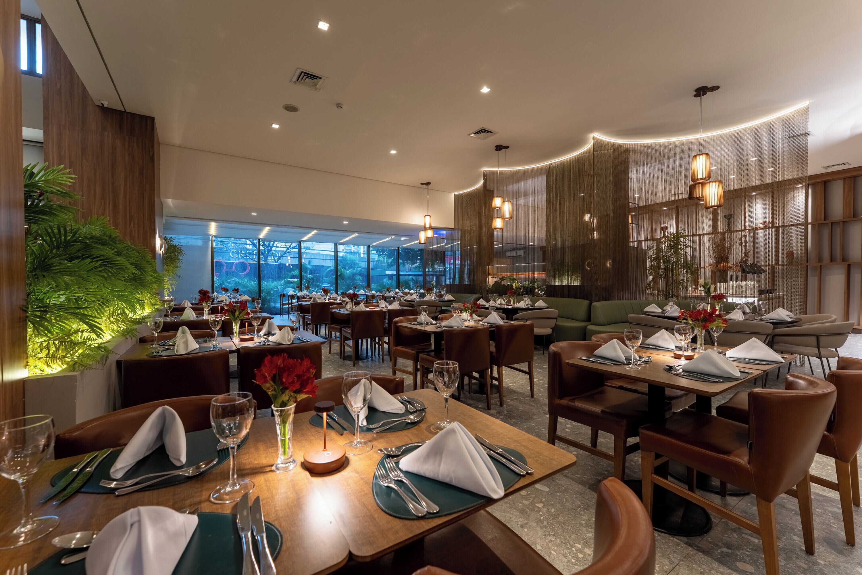 Un restaurante con varias mesas, sillas y vistas a la ciudad a través de grandes ventanales.