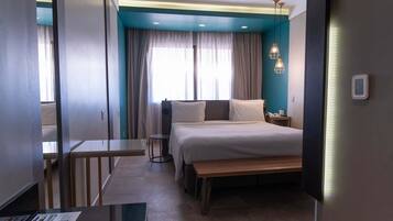 Une chambre d’hôtel moderne, équipée d’un lit, d’une table de chevet et d’un petit bureau.