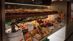 A bakery display with various baked goods and a Nutella dispenser. - Hotel Deville Prime Cuiabá (Cuiabá)