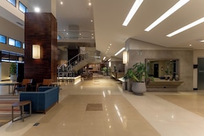 Un hall amplio con mostrador de recepción, zona de estar y una escalera que lleva a los pisos superiores.