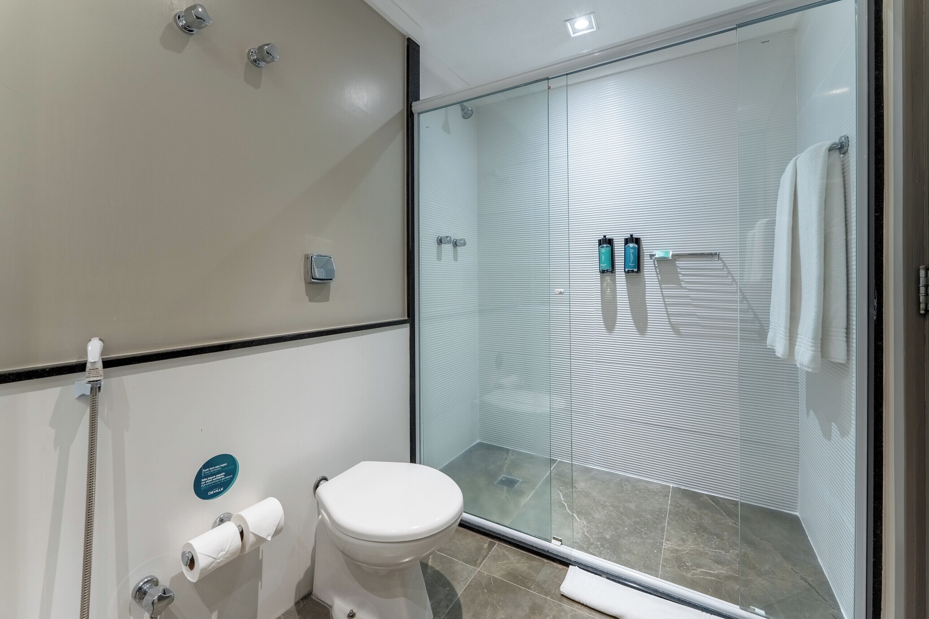 A bathroom with a toilet, a glass shower enclosure, and a towel rack.
