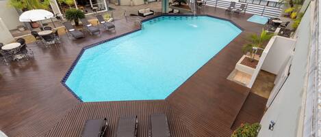 Ein Dachpool mit Holzterrasse, Liegestühlen und einem kleinen Wasserfall.