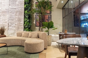 Un interior moderno con un sofá modular, una mesa redonda y una planta en maceta.
