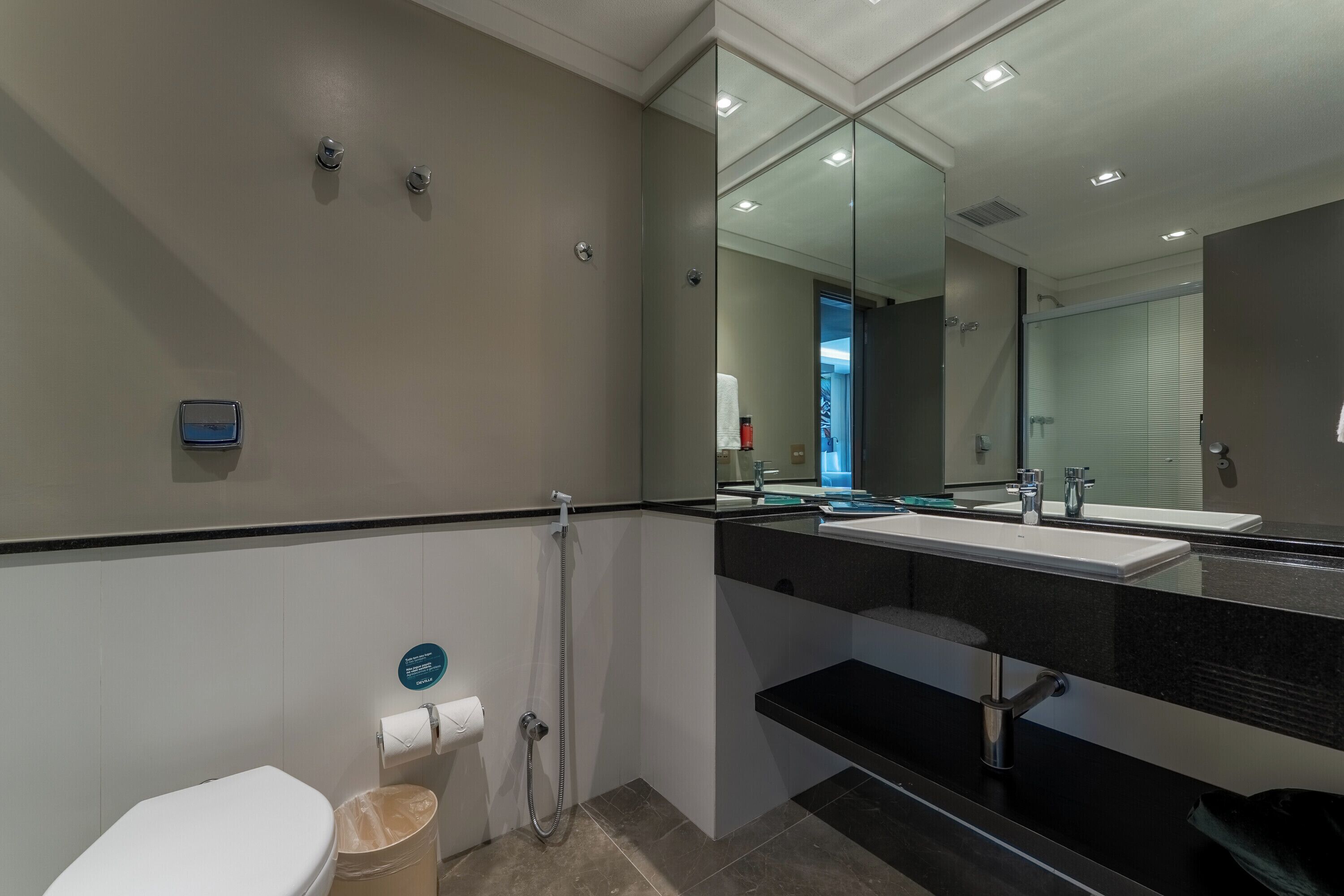 Un baño moderno con inodoro, bidé y un espejo grande.