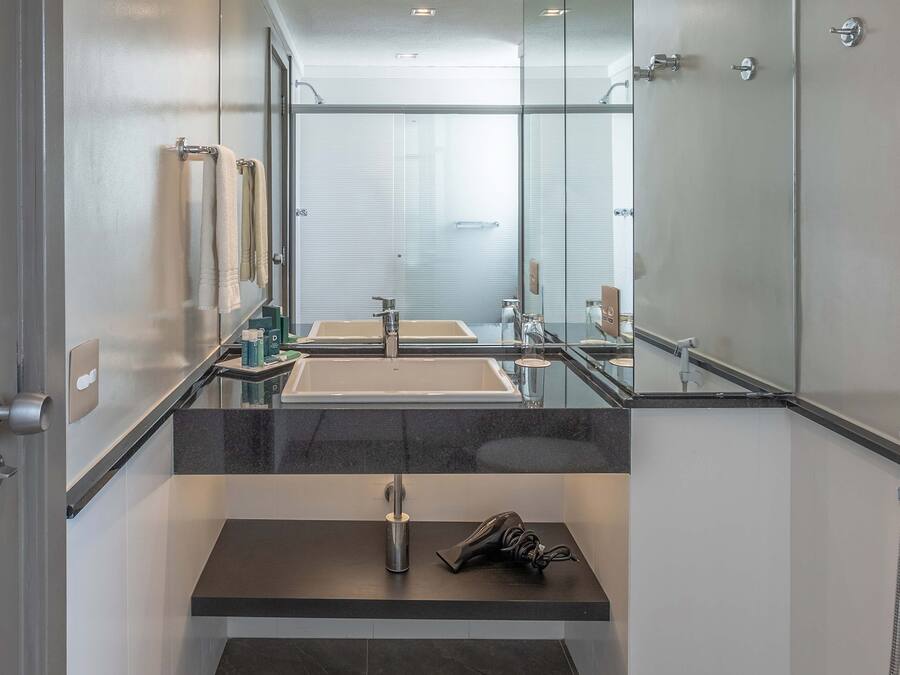 Une salle de bain moderne avec un grand miroir, deux vasques et une douche.