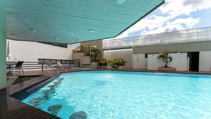 Ein Schwimmbecken mit Holzterrasse und Liegestühlen.