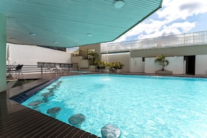 A swimming pool with a wooden deck and lounge chairs.