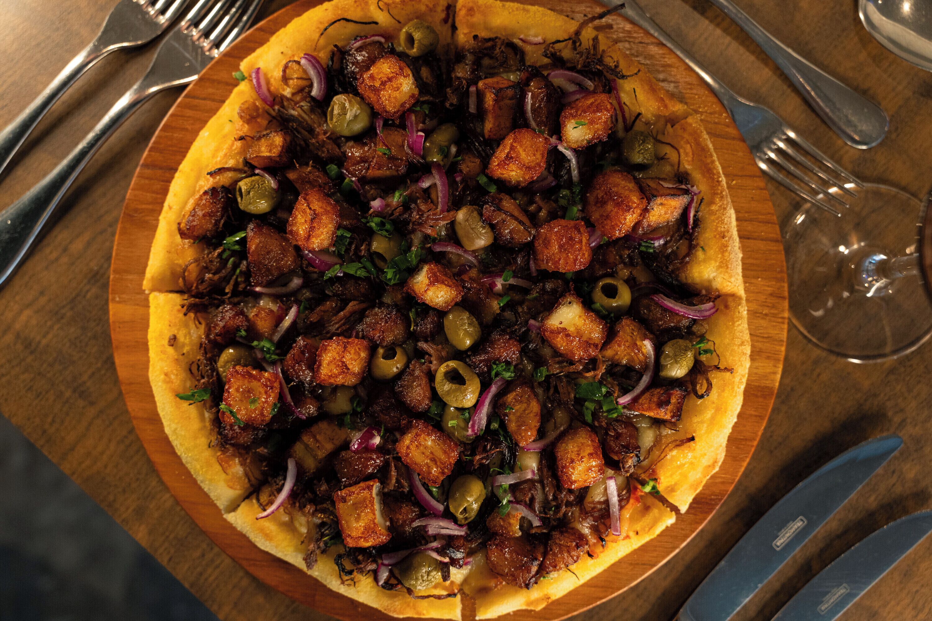 Una pizza con diferentes ingredientes sobre una tabla de madera.