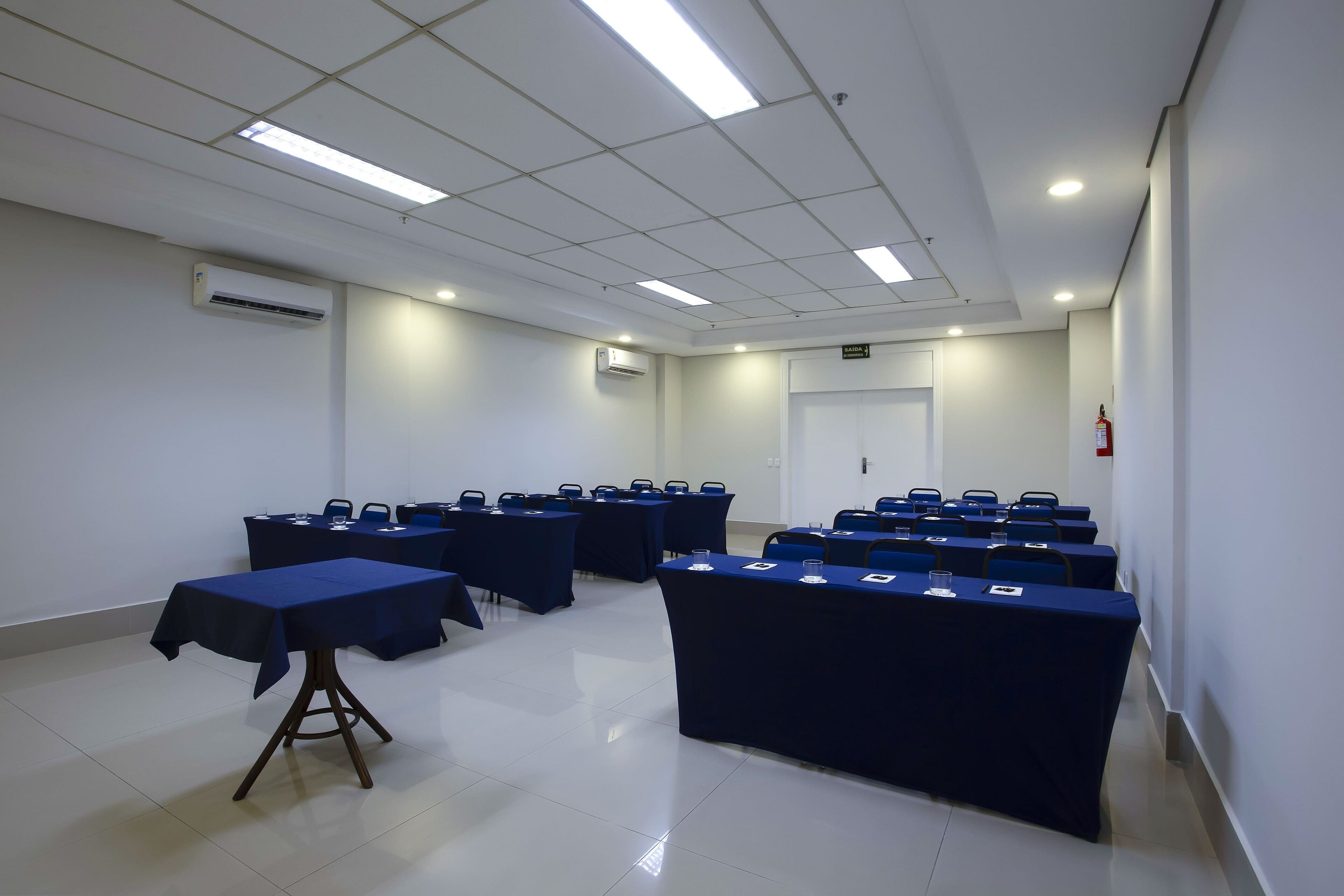 A conference room with tables and chairs, air conditioning units, and a door.