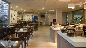 Een modern restaurant met houten tafels en stoelen, een centraal eiland met etalages en een groot raam aan de linkerkant.