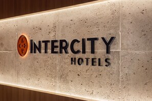 A sign for Intercity Hotels with a textured wall background and a logo on the left.