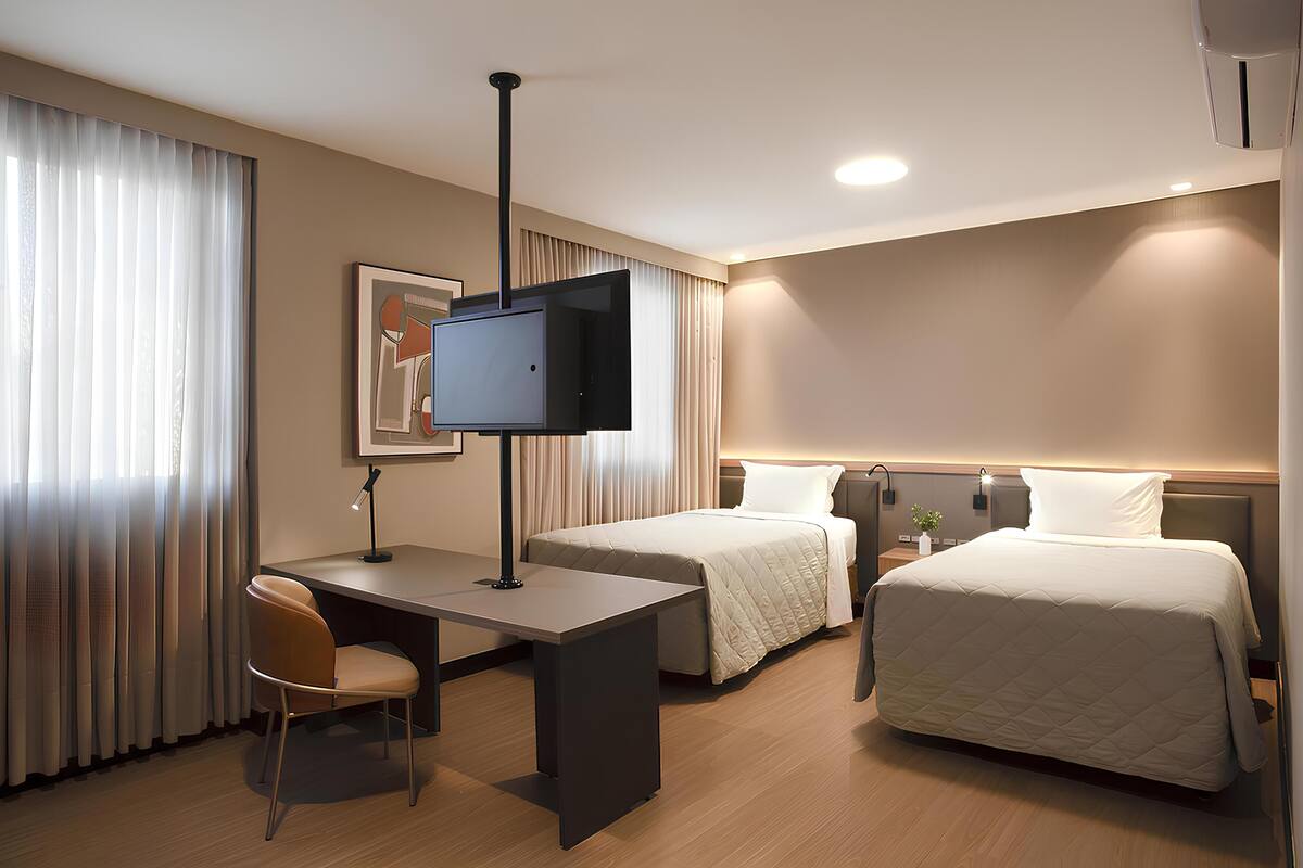 Une chambre d’hôtel équipée d’un bureau, de deux lits, d’une télévision et d’une chaise.