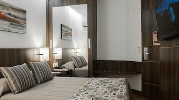 A hotel room with a bed, bedside tables, a mirror, a TV, and a wardrobe.
