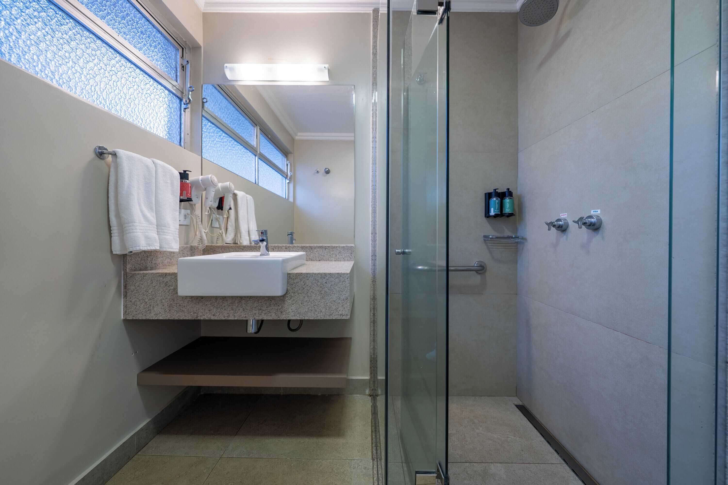 A modern bathroom with a glass shower enclosure, a sink with a countertop, and a mirror above the sink.