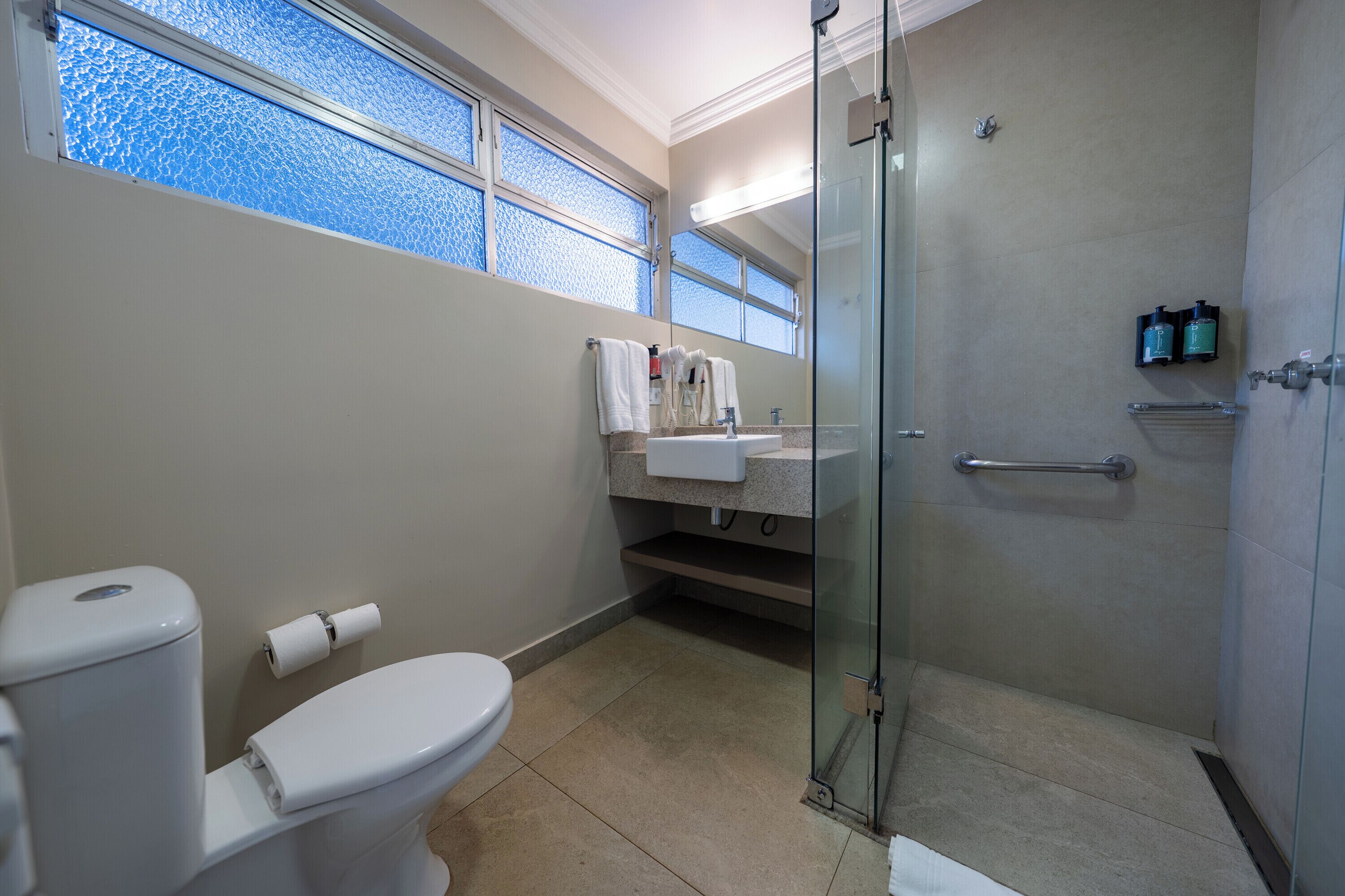 A bathroom with a toilet, a shower, and a sink.