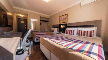 Habitación de hotel con dos camas, un escritorio, una silla, un espejo y una ventana.