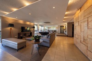 A modern living room with a sofa, a coffee table, and a television. - Hotel Deville Express Cascavel (Cascavel)