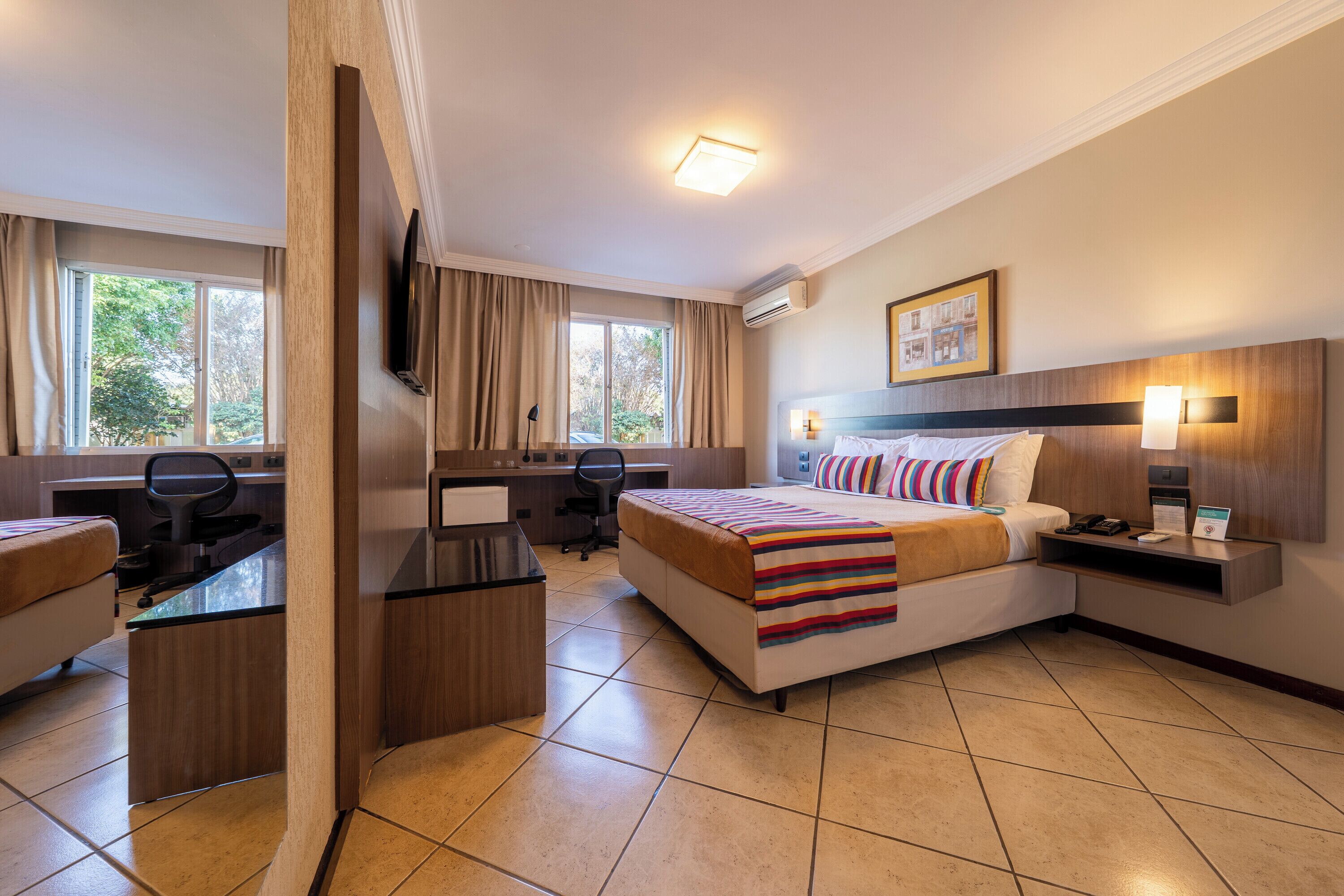 Habitación de hotel con cama, escritorio, silla y televisión.