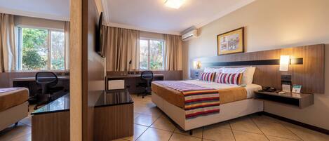 Habitación de hotel con cama, escritorio, silla y televisión.