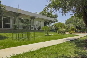 A building with a modern architectural style, a paved walkway, and a well-maintained grassy area with trees and a small playground. - Hotel Deville Express Cascavel (Cascavel)