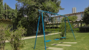 Un parque infantil con columpios y un camino pavimentado.
