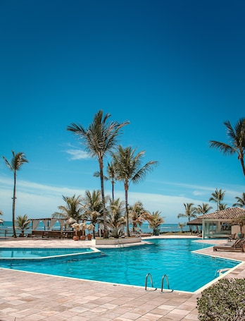 Una piscina al aire libre, sombrillas, sillones reclinables de piscina