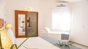 Un dormitorio con cama, lámpara de noche y ventana con cortinas.
