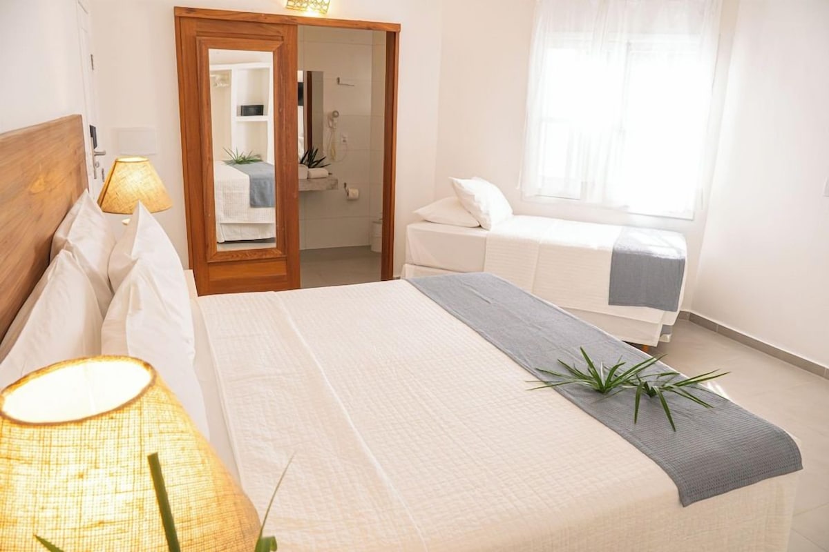 A bedroom with a bed, bedside lamp, and a view of the bathroom.