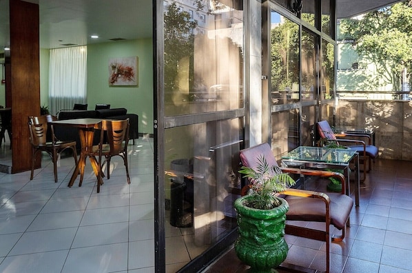A modern interior with a dining area, a green plant centerpiece, and large windows offering a view of the outdoors.