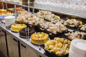 Monipuolinen buffet, jossa on tarjolla erilaisia ruokia, kuten leivoksia, makeisia ja hedelmi ä.
