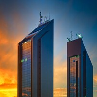 Dos rascacielos modernos con fachadas de vidrio reflectante y antenas en la parte superior.