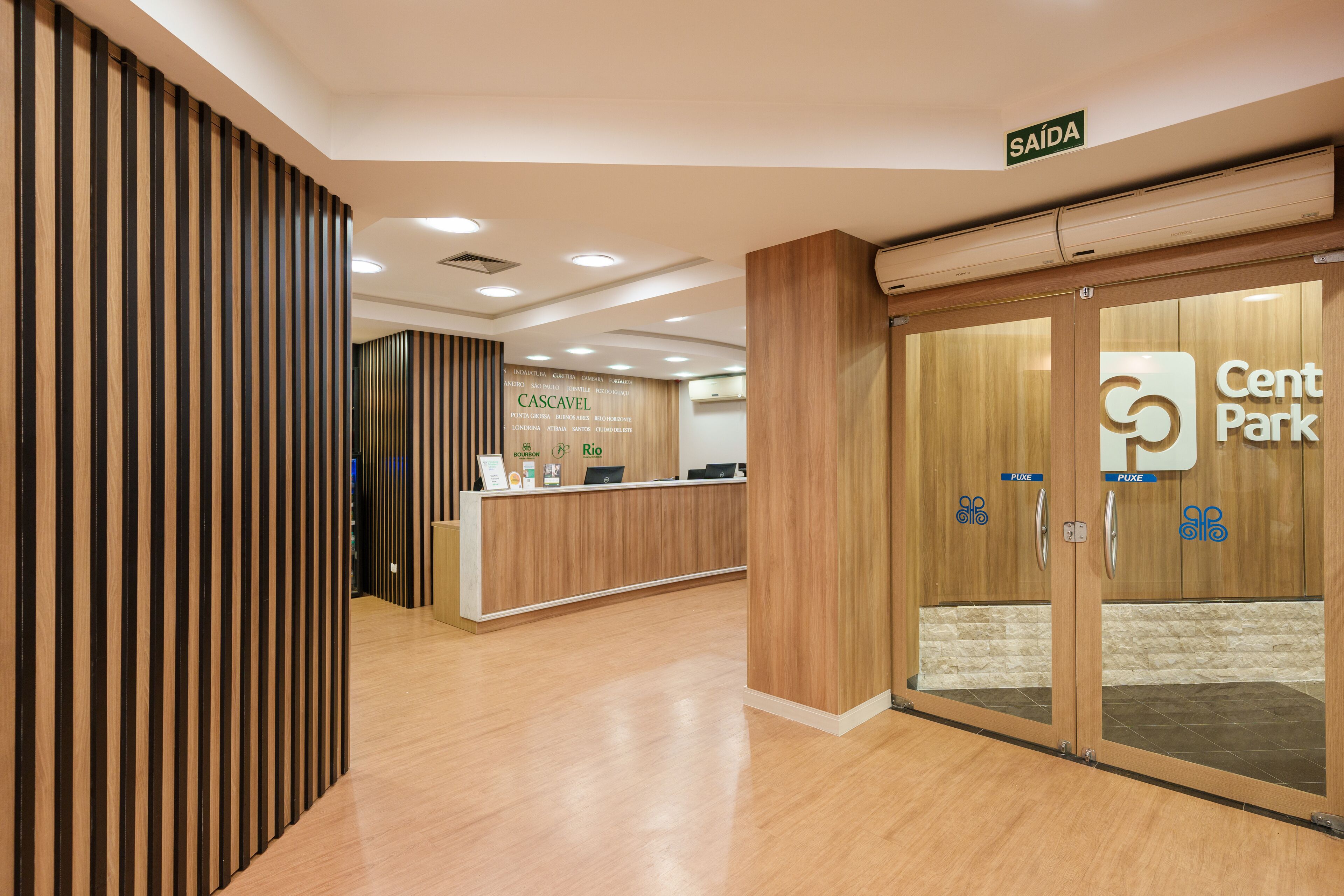 A reception area with a wooden reception desk, a sign for 'Cascavel', and a 'Cent Park' sign on the door.