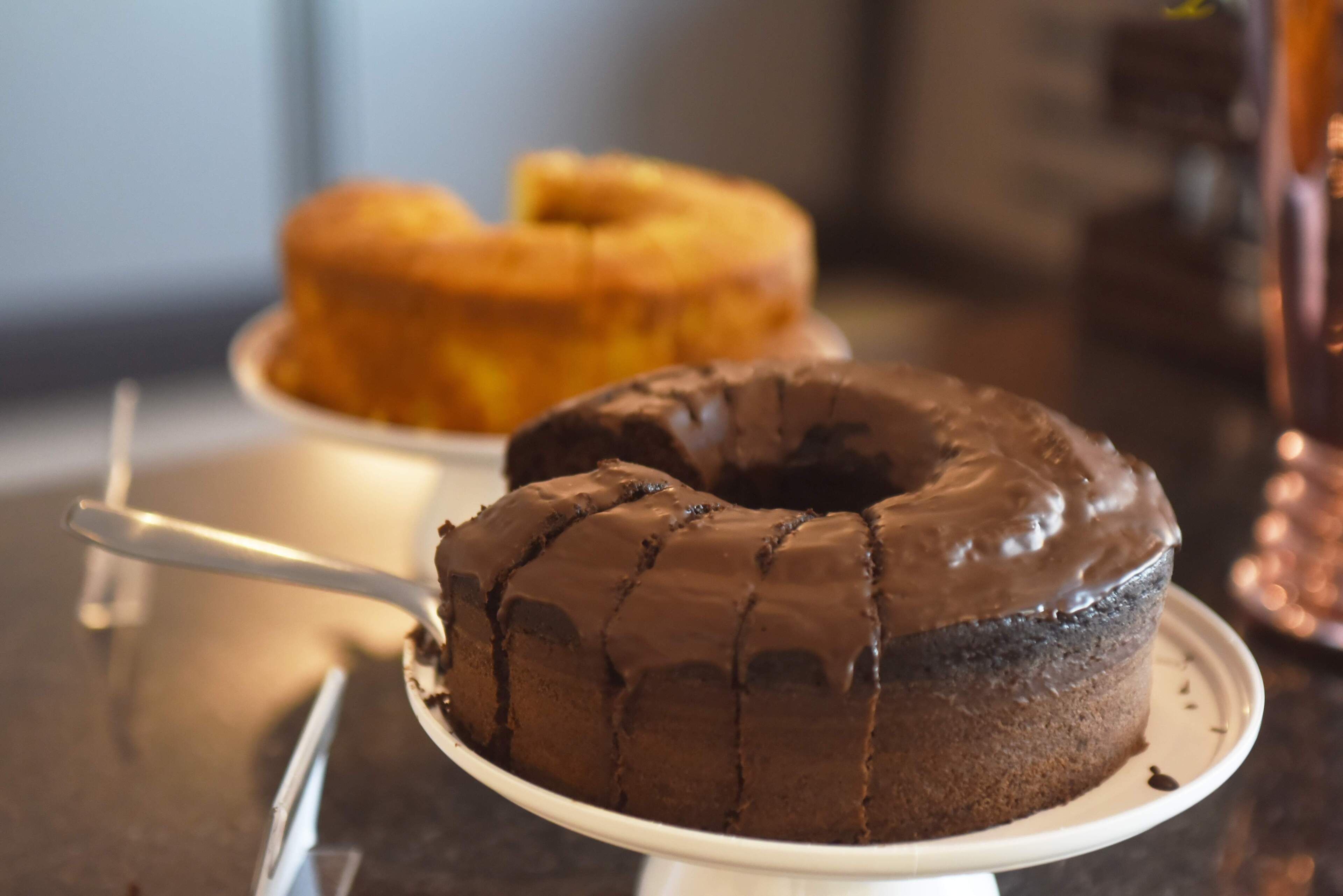 Un pastel de chocolate con cobertura de chocolate sobre un plato blanco.