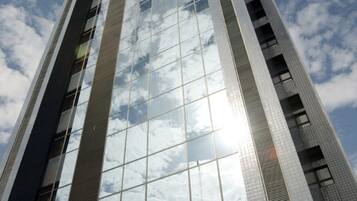 Un edificio alto y moderno con ventanas de vidrio reflectante y un cielo despejado al fondo.
