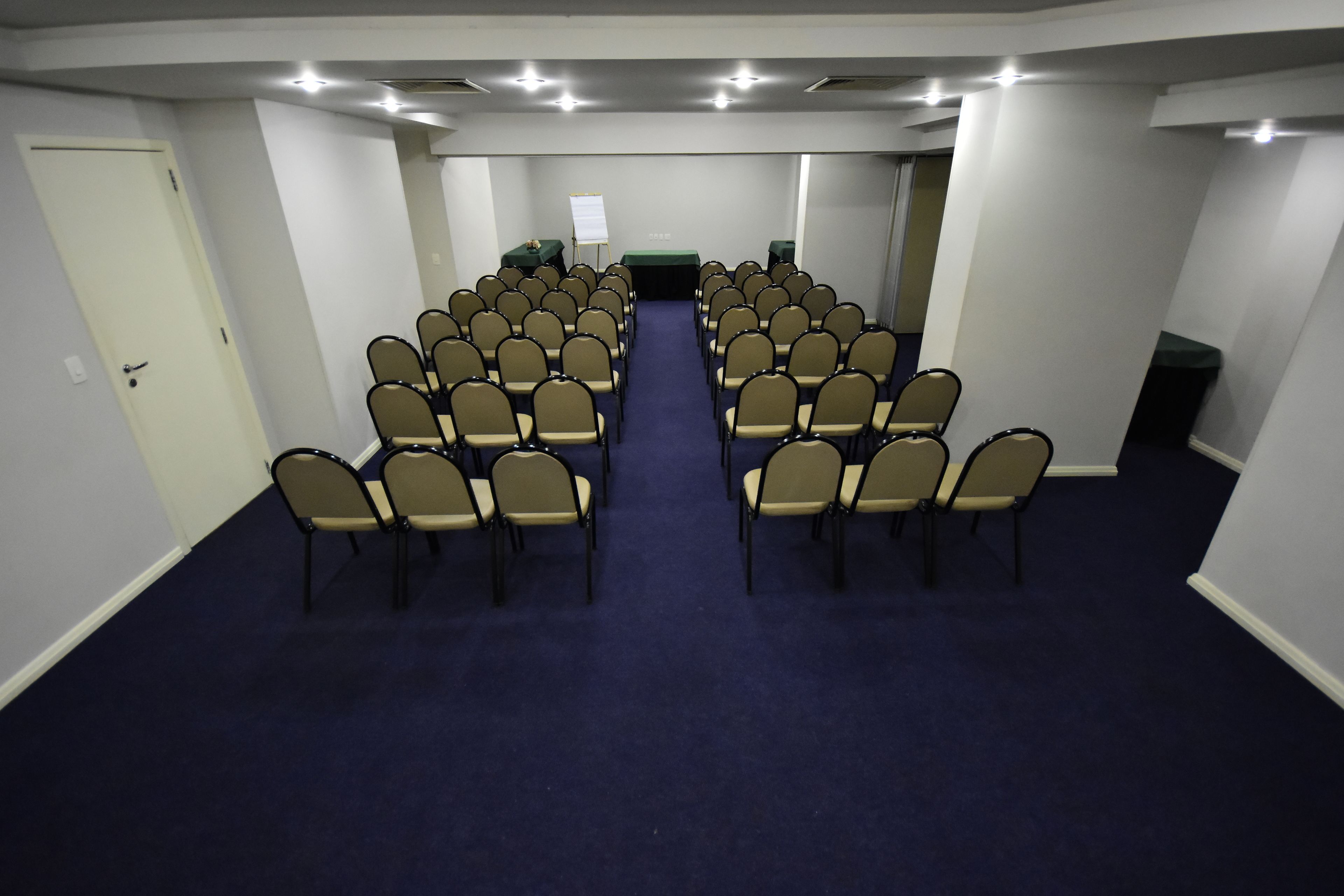 A conference room with rows of chairs, a whiteboard, and a projector screen.