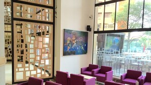 A lobby with purple seating, a large window, and a decorative wooden partition. - Hotel Dann Cali (Cali)