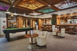 Un área de bar con mesa de billar, taburetes y barra.