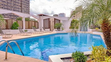 Relax by the pool surrounded by lush greenery and lounge chairs.
