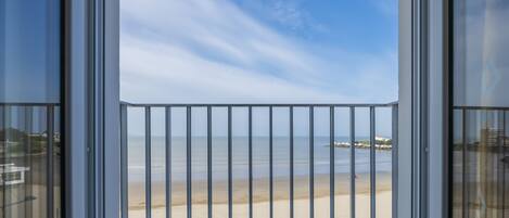 A balcony with a view of a beach and ocean.