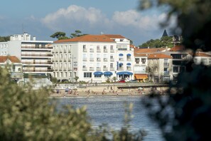 Un hôtel situé sur la côte, avec plusieurs étages, des balcons et une vue sur la plage.