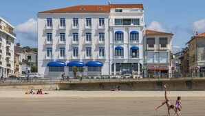 A multi-story hotel with balconies, a beach in the foreground, and a clear sky. - CERISE Royan - Le Grand Hôtel de la Plage (Royan)