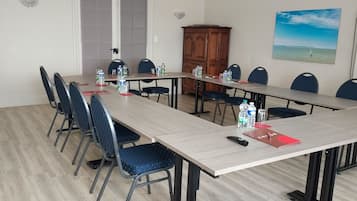 Un salón de conferencias con una larga mesa, sillas, botellas de agua y una carpeta roja sobre la mesa.