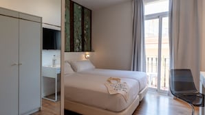 Une chambre d’hôtel équipée d’un lit, d’un bureau, d’une chaise, d’une télévision et d’un balcon.